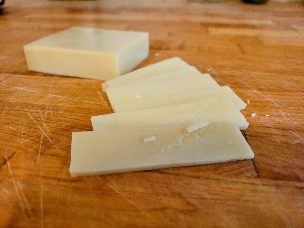 Gruyere cheese slices on butcher block